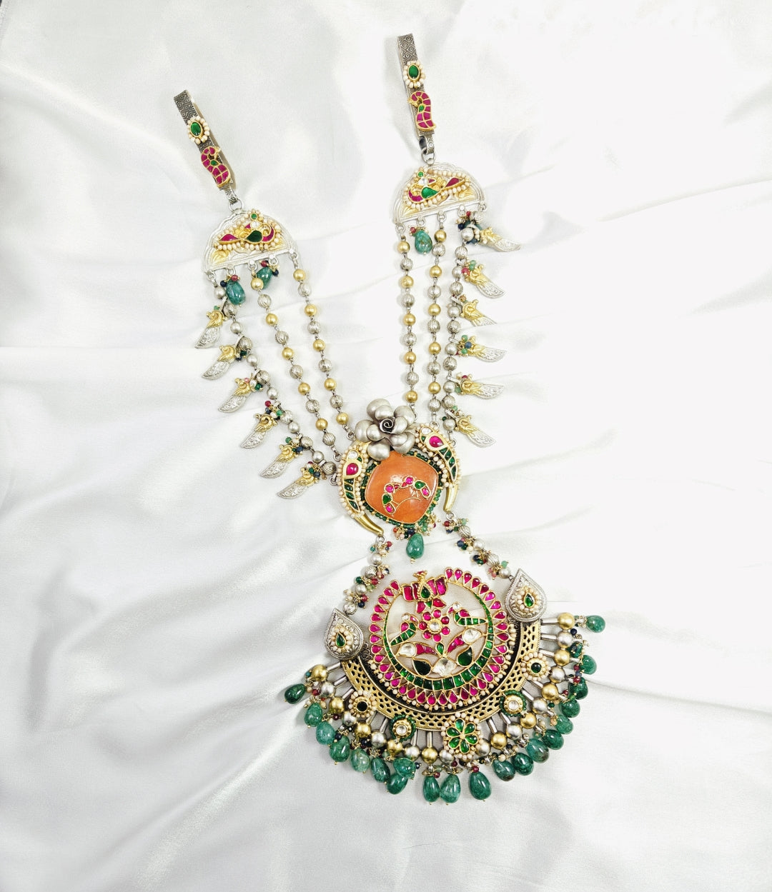 Decorative necklace with colorful gemstones on a white fabric background